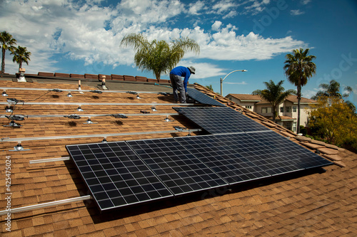 Workers installing solar panels on a tile roofon a sunny day photo