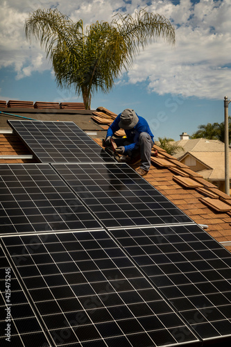 Wallpaper Mural Workers installing solar panels on a tile roofon a sunny day Torontodigital.ca