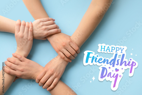 Women holding hands together on color background. Friendship Day celebration