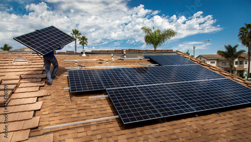 Workers installing solar panels on a tile roofon a sunny day photo