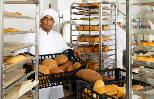Male baker with box of hot bread at bakery