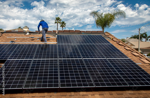 Workers installing solar panels on a tile roofon a sunny day photo