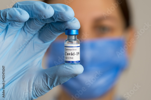 Female doctor holds syringe and coronavirus vaccine vial.