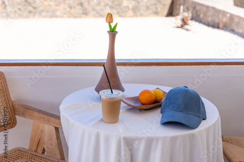 Coffee, hat, fruit and vases are placed on the table by the beach.