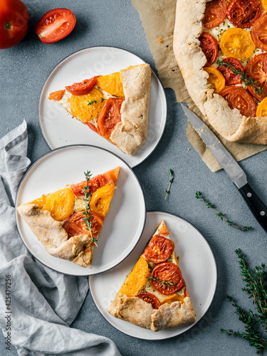 Savory fresh homemade tomato tart or galette.Ideas and recipes for healthy lunch,appetiezer- whole wheat or rye-wheat pie with tomatoes,parmesan cheese,mozzarella.Top view or flat lay.Vertical.
