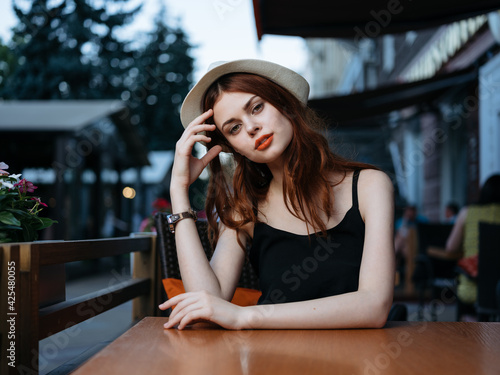 Romantic woman in a cafe on the street and bright makeup watches a white hat © SHOTPRIME STUDIO