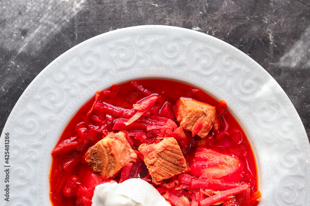 Red borsch with vegetables and meat in a white plate. Tomato soup. Dark background. Delicious healthy lunch. Close up Red borsch with vegetables and meat in a white plate. Tomato soup. Dark background. Delicious healthy lunch. Close up