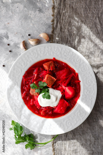 Red borsch with vegetables and meat in a white plate. Tomato soup. Light background. Delicious healthy lunch. Top view