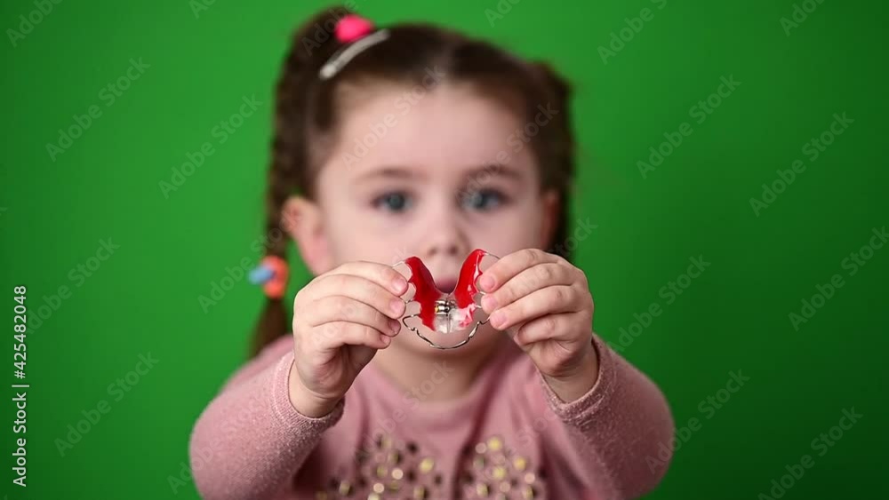 The child examines and demonstrates a dental plate to straighten crooked teeth. The child examines and demonstrates a dental plate to straighten crooked teeth.