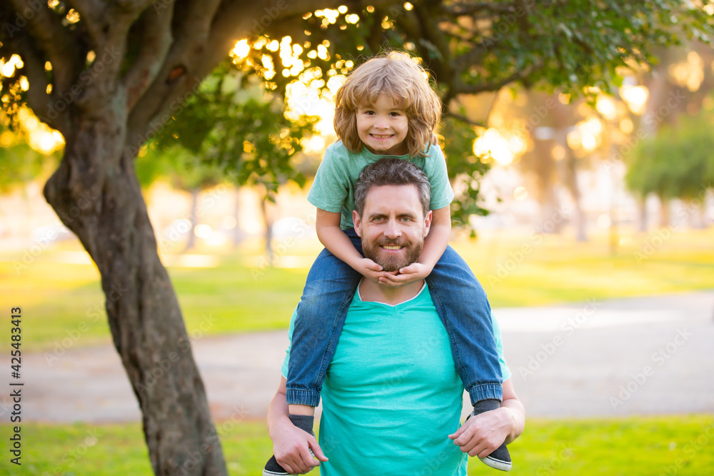 Cute boy sitting on fathers shoulders. Childhood and parenthood kids concept. Happy father and son playing together outdoor. Cute boy sitting on fathers shoulders. Childhood and parenthood kids concept. Happy father and son playing together outdoor.
