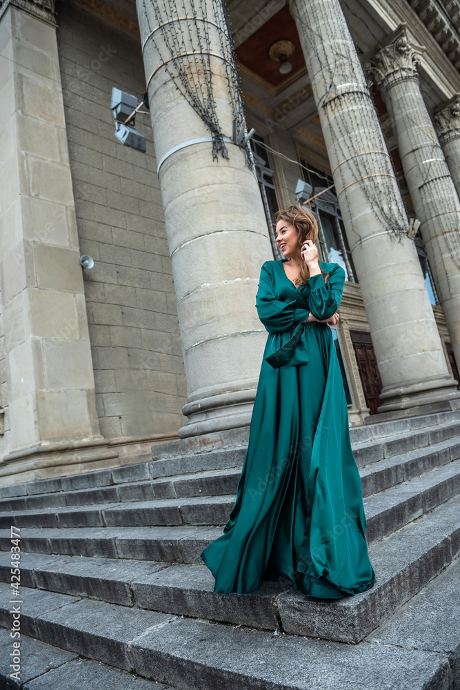 full length young elegant woman in beautiful green gress standing in stone   stair