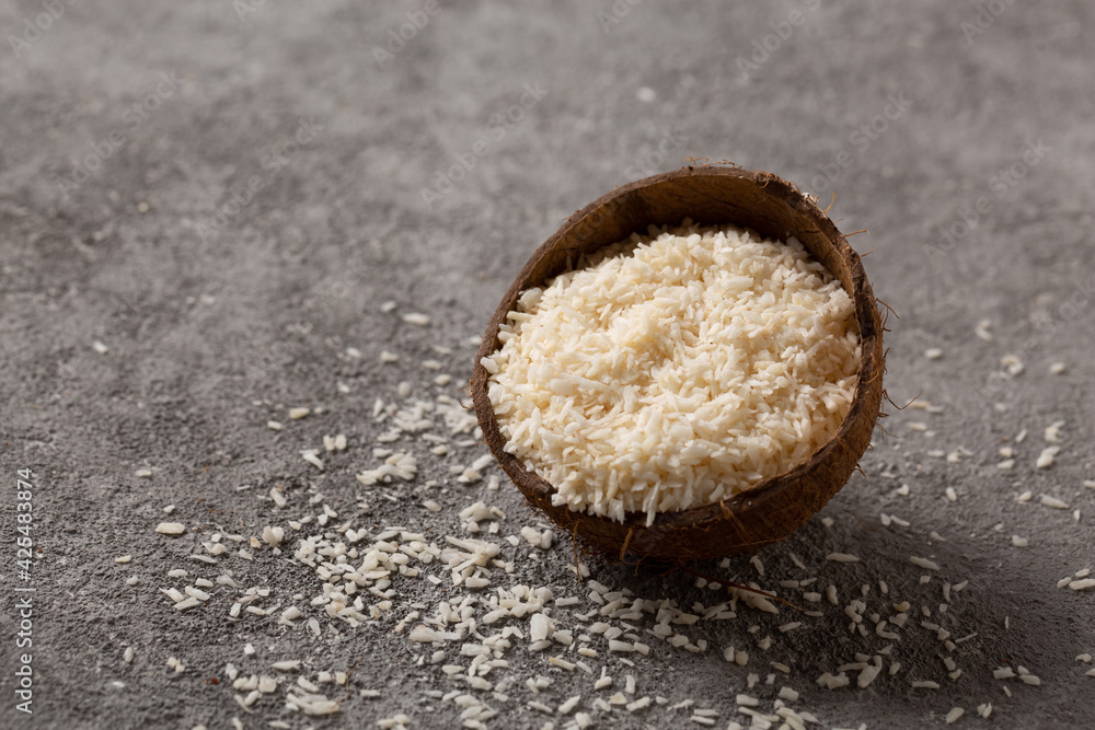 Chopped coconut with coconut flakes on a gray concrete background. Chopped coconut with coconut flakes on a gray concrete background.