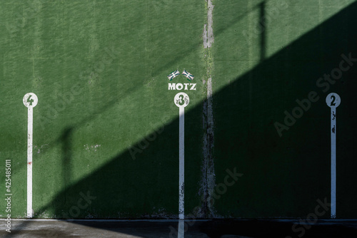 fronton wall in the Basque ball sport, in which the game marks are painted with the numbers 3 in the middle and 2 and 4 on both sides. Above the number 3 there are two Basque flags and the word, Motz, photo