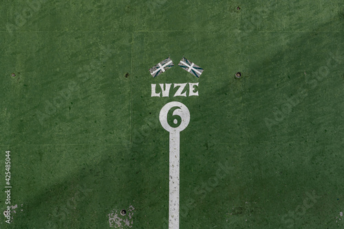 fronton wall in the Basque ball sport, in which the game marks with the number
 6 Two Basque flags appear above number 6 and the word, Luze, strong, in Basque, not strong enough, painted in negative i