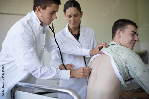 Young student checks a patient's lungs in a hospital room.