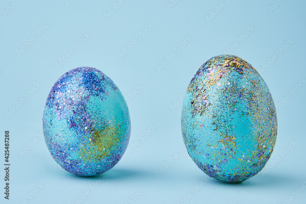 Blue painted eggs with bright shiny gliter on blue background Blue painted eggs with bright shiny gliter on blue background