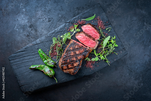 Traditional barbecue dry aged sliced wagyu roast beef with chili and red wine salt served as top view on a charred wooden board with copy space