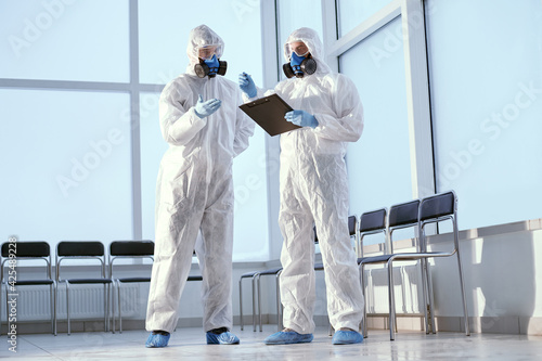 researchers in protective suits discussing something standing in the lab.