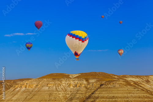 Hot air balloon flying over rocky landscape at sunrise - Cappadocia Turkey