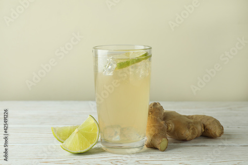 Glass of ginger beer and ingredients on white wooden table