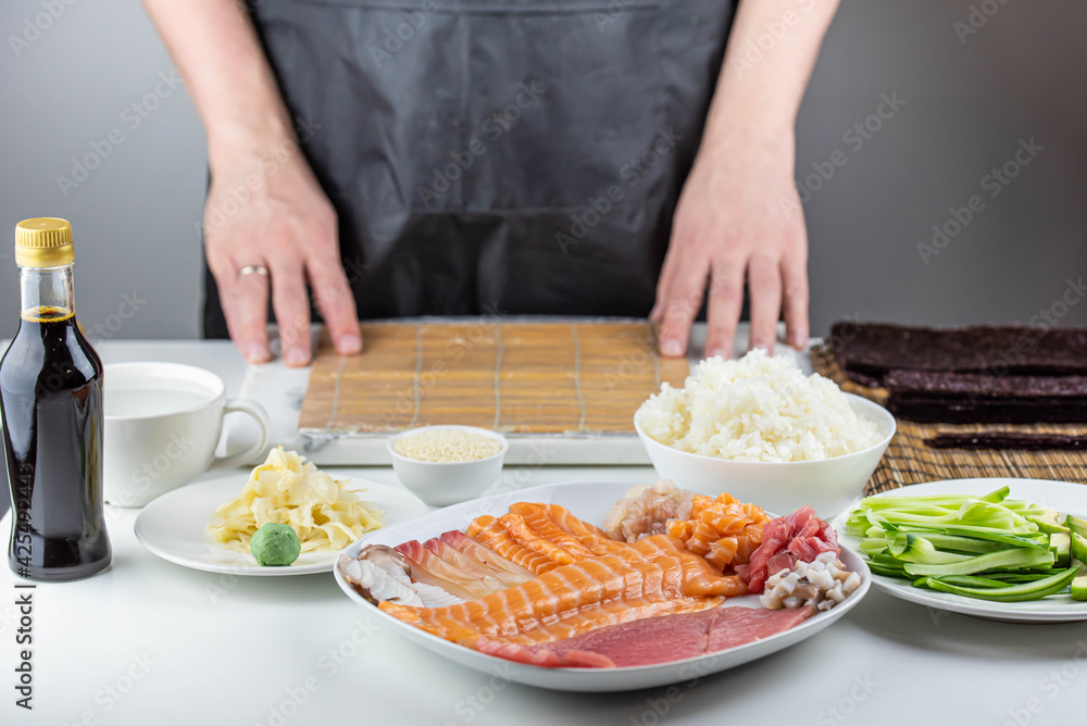 Close up of sushi chef hands preparing japanese food. Man cooking sushi at restaurant. Traditional asian seafood rolls on cutting board.