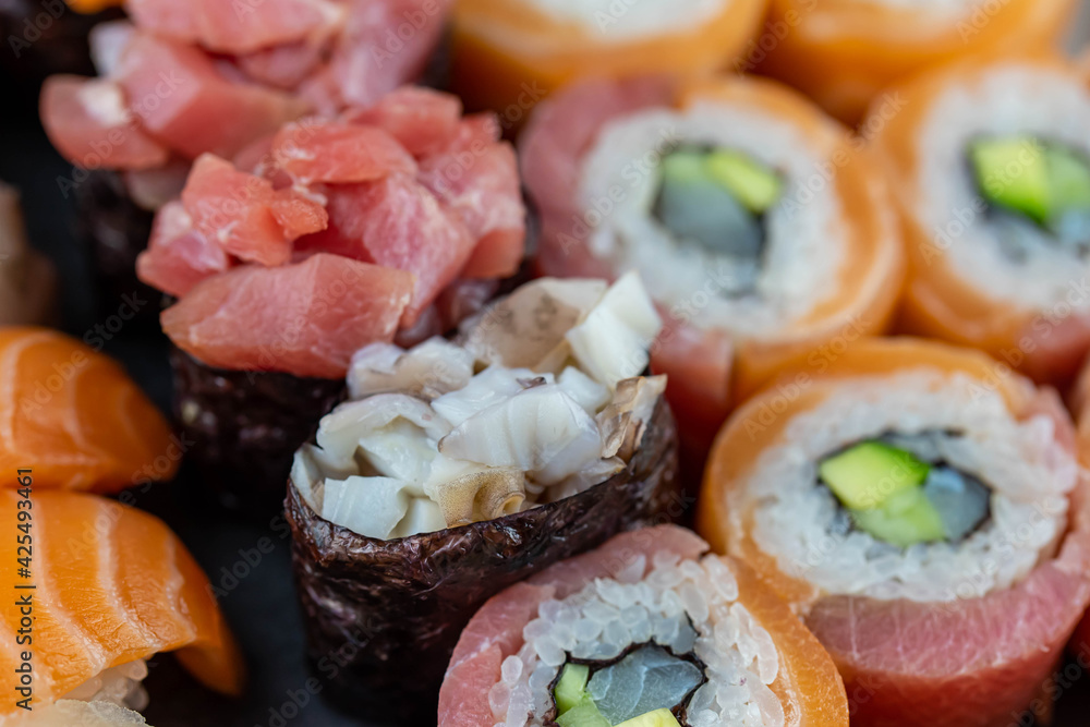 Sushi rolls prepared by professional asian chef with traditional Japanese ingredients. Salmon fish, rice, vegetables, sesame seeds. Sushi cooking and seafood making concept Sushi rolls prepared by professional asian chef with traditional Japanese ingredients. Salmon fish, rice, vegetables, sesame seeds. Sushi cooking and seafood making concept
