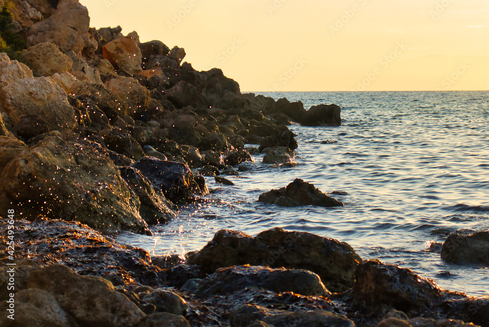 Obraz premium Water spraying over the rocks at Golden Bay, Malta at sunset.