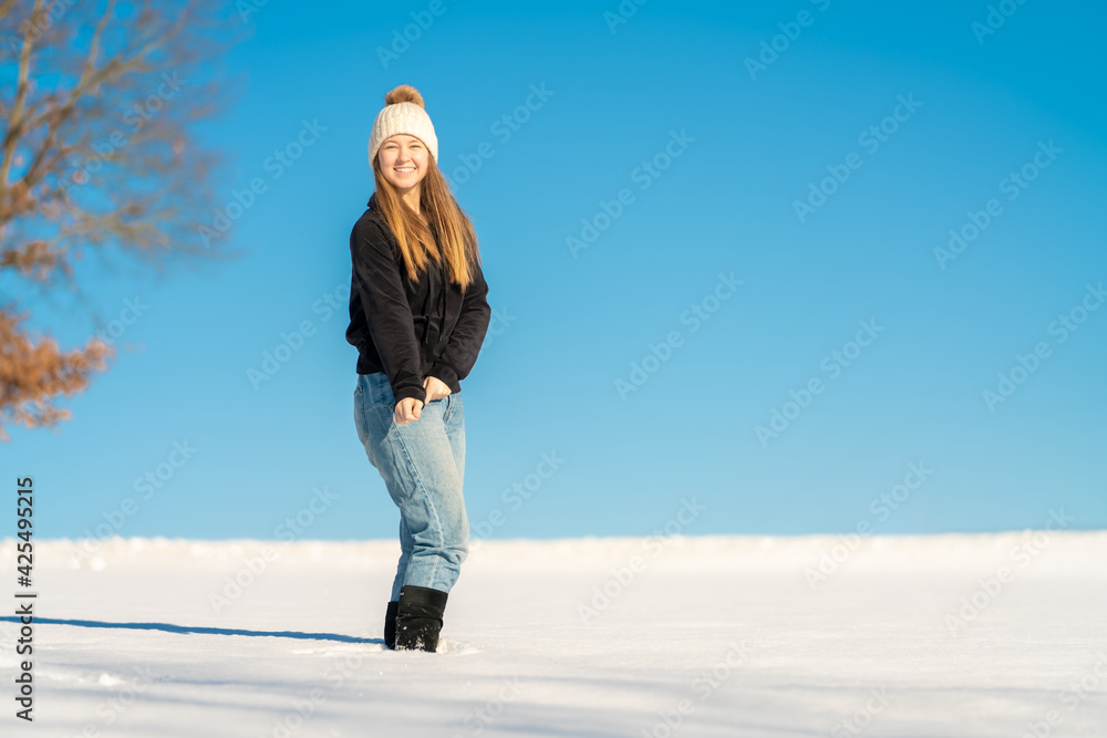 Hübsches junges Teenager Mädchen posiert im hellen, weißen Schnee vor blauem Himmel Hübsches junges Teenager Mädchen posiert im hellen, weißen Schnee vor blauem Himmel