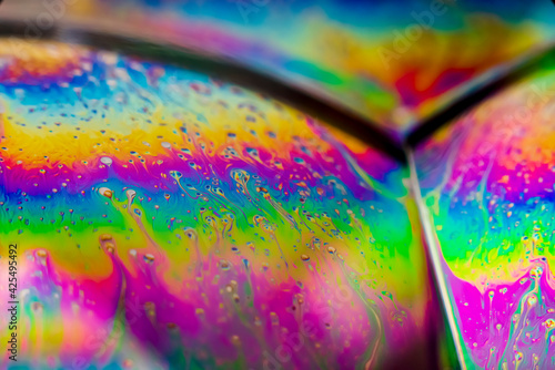 The colorful close-up surface of a soap bubble with weird psychedelic background and patterns. Vivid rainbow colors in weird and strange patterns. 