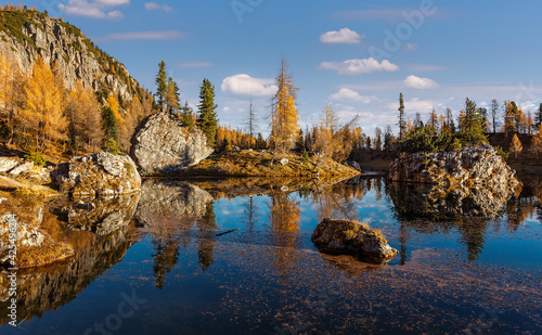 Impressively beautiful Fairy-tale mountain lake in Alps. Beautiful rock Islands with fir trees under sunlight, reflection in calm water of Federa Lake and perfect blue sky on background. Dolmites alps