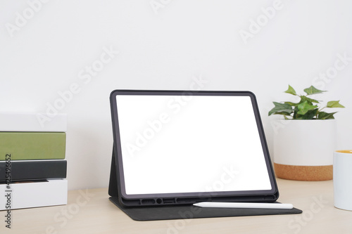 Blank screen tablet with digital pencil on the table.