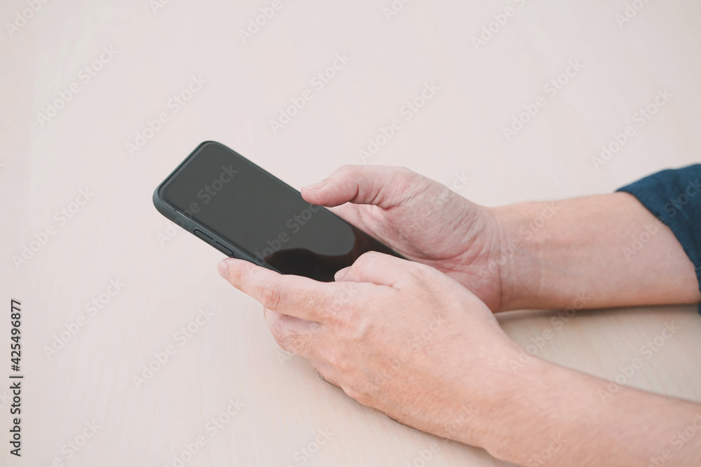 Close up of a man using mobile smart phone on wood table. Close up of a man using mobile smart phone on wood table.