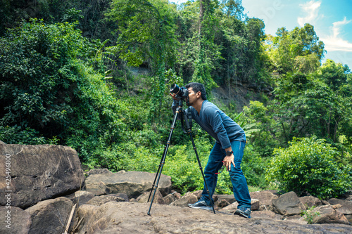 Outdoor Photographer use camera on tripod for shooting in rainforest.
