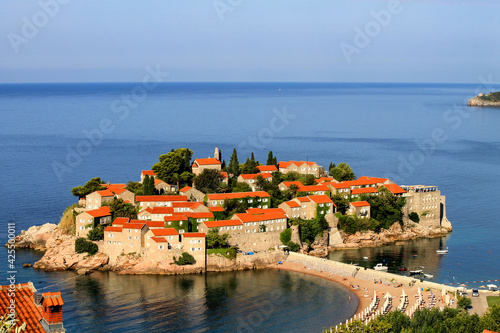 Sveti Stefan, a beautiful resort island in Adriatic Sea in Montenegro. Old houses with red, orange roofs in the bay. Tourist symbol of Montenegro in spring and summer