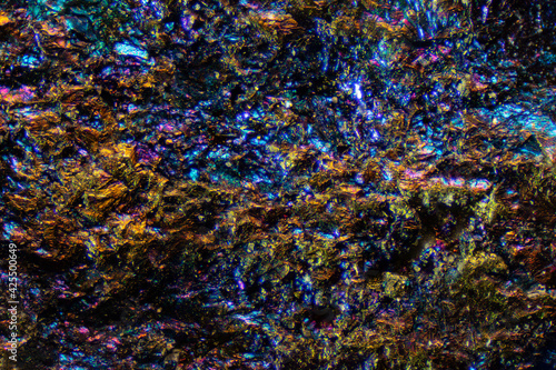 Abstract colorful background image of a mineral surface. Microscopic image of colorful copper ore. Bornite, also known as peacock ore.