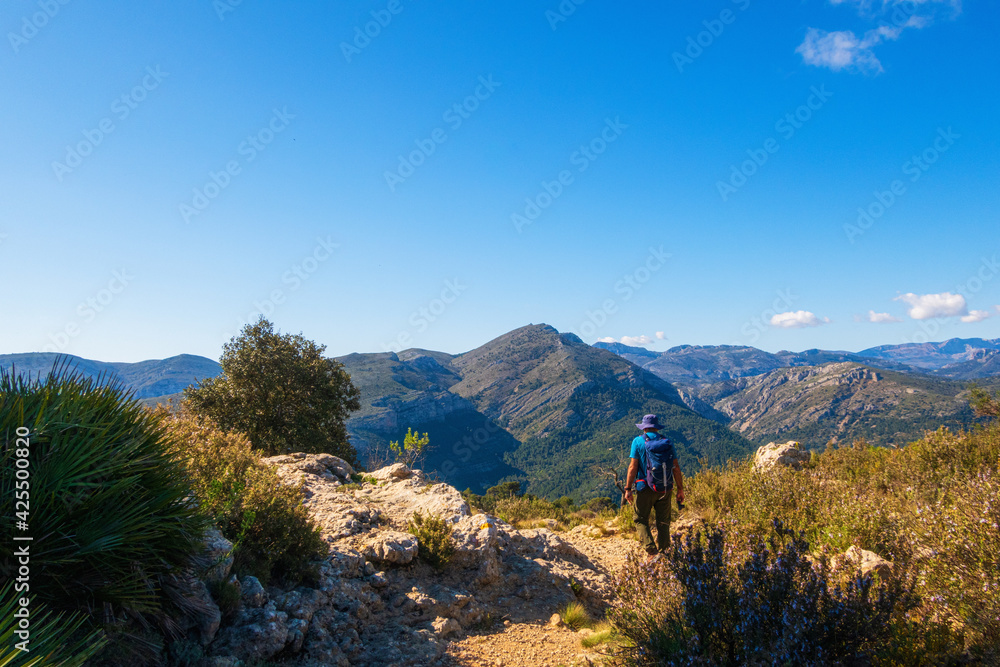 Hikers walking on mountains, in a sunny spring day. In La vall de laguar, Alicante (Spain)