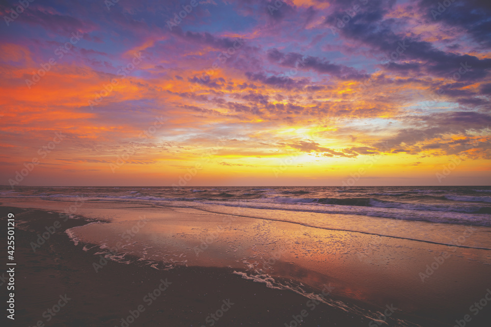 Seascape in the early morning. Sunrise over the sea. Sandy beach with the beautiful dramatic sky during sunrise. Nature landscape