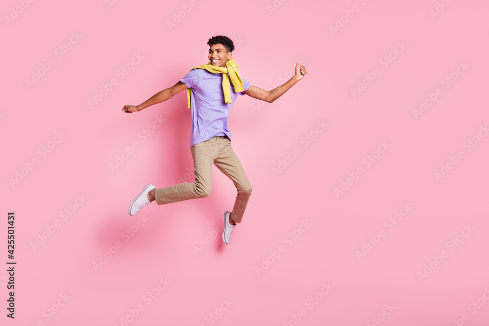 Full size photo of young handsome happy positive smiling man jumping look copyspace isolated on pink color background Full size photo of young handsome happy positive smiling man jumping look copyspace isolated on pink color background