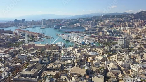 Aerial panoramic drone view of buildings and streets surrounding Port of Genoa. Cruise ships and ferries in port. Old famous city of Italy with roofs of old buildimìngs, historical streets. 4K video photo