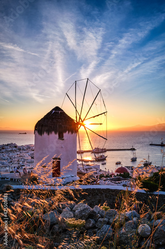 Obraz na płótnie Famous traditional white windmill overlook port and harbor of Mykonos, Cyclades, Greece at sunset sky. Beautiful sky, sun, sea, horizon, town, island w salonie