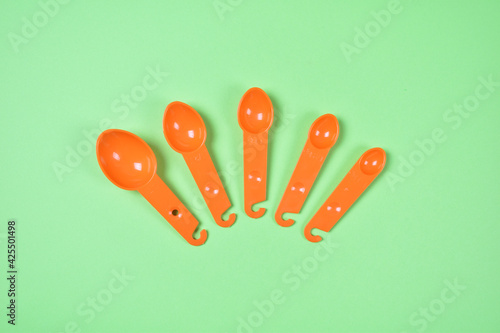 Kitchen measuring orange spoons on green background