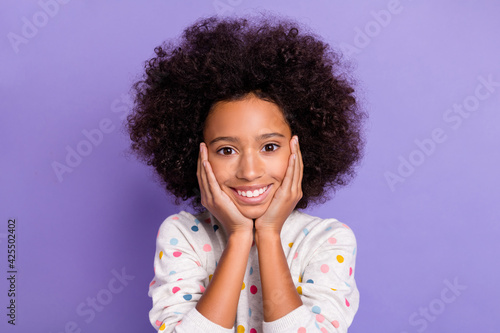 Photo portrait of little girl touching cheeks cute smiling in dotted shirt isolated on pastel purple color background
