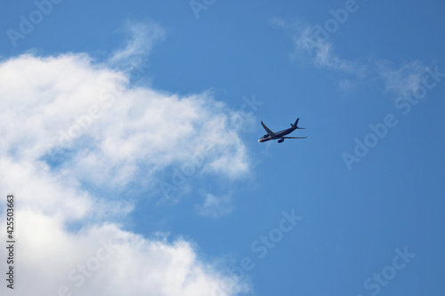 Airplane flying in the blue sky with clouds. Commercial plane at flight, travel concept