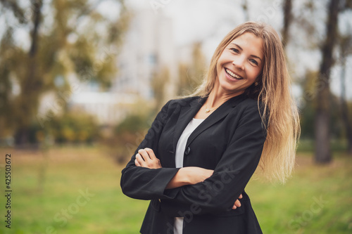 Outdoor portrait of happy businesswoman. Blond businesswoman is standing outdoor and smiling. © djoronimo