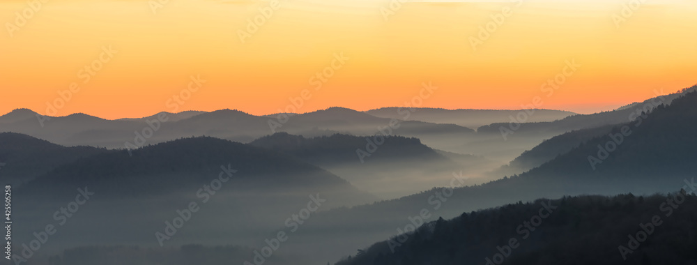 foggy, misty valley short before sunrise, beautiful orange yellow lighted sky