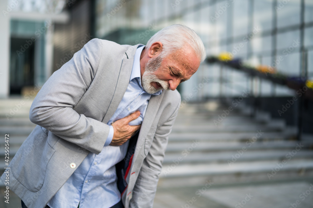 Senior businessman is having stroke in front of company building. Senior businessman is having stroke in front of company building.