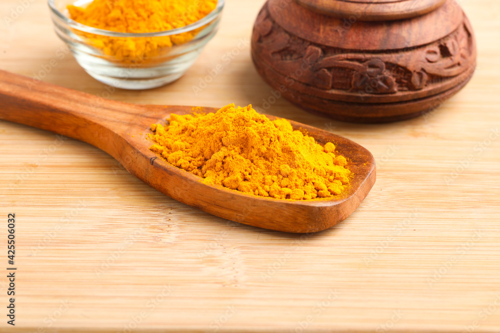 Turmeric powder in wooden spoon and glass bowl on white background. Turmeric powder in wooden spoon and glass bowl on white background.