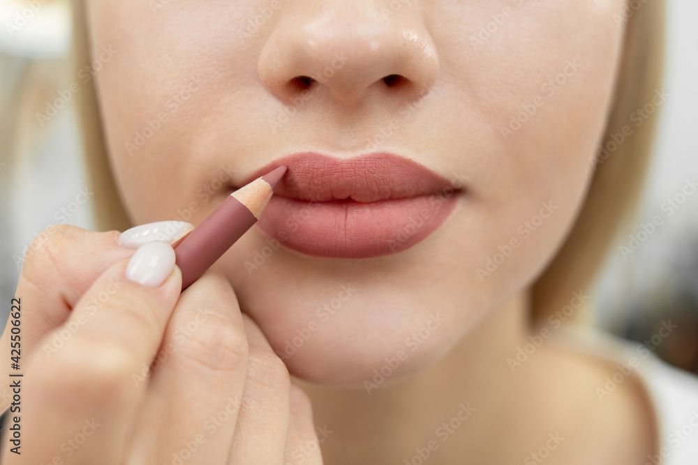 Obraz premium Lip makeup. Close-up of a cosmetologist painting her lips with a pencil after permanent makeup.