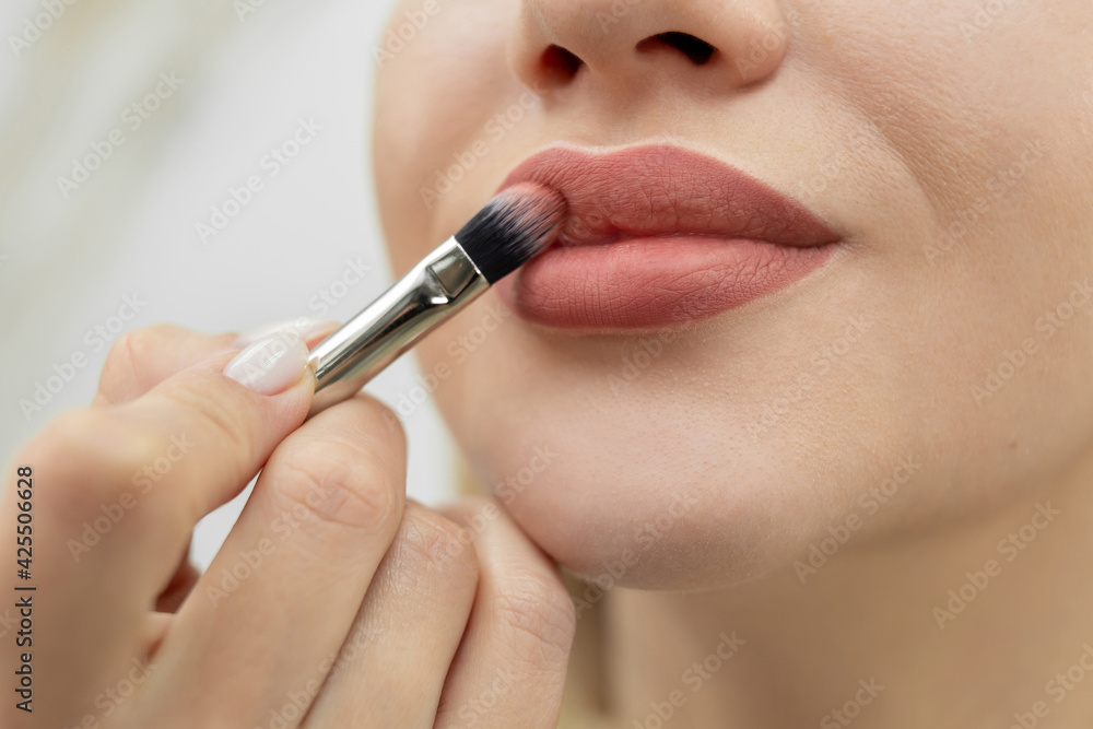 Make-up artist cosmetologist paints her lips after a permanent makeup procedure.