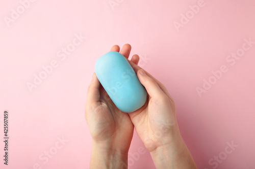 Woman hand holding a blue soap bar on a pink background